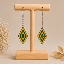 Load image into Gallery viewer, Aurora Step wooden earrings shown from the front on a light wood stand, with vivid yellow hand-painted wood, green resin accents, silver-tone chains and hooks.