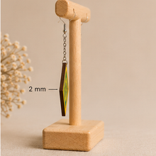 Load image into Gallery viewer, Side view of Aurora Step wooden earrings on a light wood stand, showing the 2 mm wood thickness, silver-tone chain and hook.