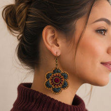 Load image into Gallery viewer, Crimson Roots embroidered wooden earring worn with a burgundy sweater, showing its size and scale.