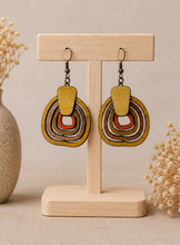 Load image into Gallery viewer, Earth Echoes hand-painted wooden earrings displayed front-facing on a light wood stand.