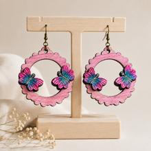 Load image into Gallery viewer, Mariposa Serena layered butterfly wooden earrings on a light wood stand