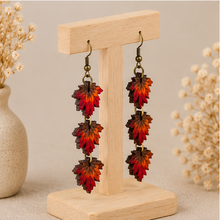 Cargar imagen en el visor de la galería, Angled view of Autumn Ember hand-painted wooden earrings on a light wood stand.
