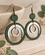 Load image into Gallery viewer, Lunar Dance wooden earrings shown at an angle to highlight the articulated green and white moving circle design
