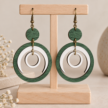 Load image into Gallery viewer, Lunar Dance articulated green and white wooden earrings on a light wood stand with a clean neutral background
