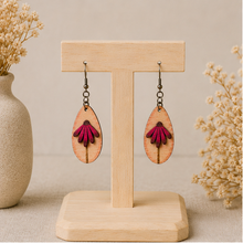 Load image into Gallery viewer, Mauve Blossom wooden earrings displayed front-facing on a light wood stand, showing the layered deep mauve petals and engraved stem.
