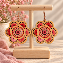 Load image into Gallery viewer, Natural Splendor hand-embroidered wooden flower earrings in red and pink on a light wood stand with bronze-tone hooks
