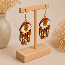 Load image into Gallery viewer, Radiant Eye hand-painted wooden earrings shown at a steeper angle on the standard light wood stand to clearly display the 2.5 mm wood thickness.

