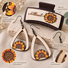 Load image into Gallery viewer, Detail view of the Sunflower Blessed set showing layered hand-painted sunflowers, laser engraving, natural wood grain, gunmetal-tone hooks, and the engraved Blessed hair clip.
