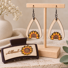 Load image into Gallery viewer, Sunflower Blessed matching set with lightweight wooden earrings on a light wood stand and a 3.5-inch dark brown hair clip with layered hand-painted sunflower detail.

