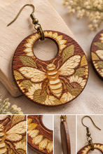 Load image into Gallery viewer, Close-up of Sunset Honey Bee wooden earring showing natural wood grain, laser-engraved bee and sunflower details, and hand-painted accents
