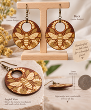 Load image into Gallery viewer, Front, back and angled views of Sunset Honey Bee wooden earrings showing the same engraved design on both sides and 2 mm thickness

