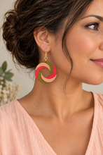 Load image into Gallery viewer, Model wearing SunTwist Joy lightweight wooden swirl earrings in coral, peach and olive with a pale peach top and gold-tone hooks
